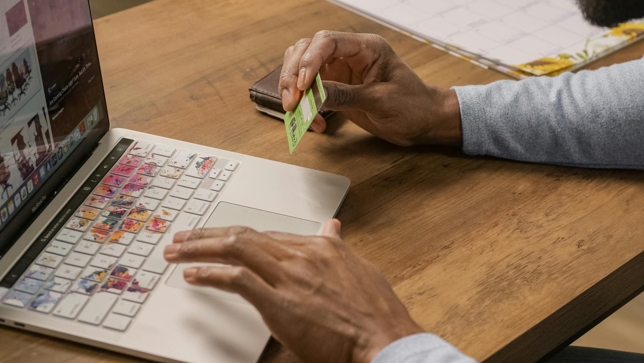 Close-up of hands using a laptop and holding a credit card for online shopping.